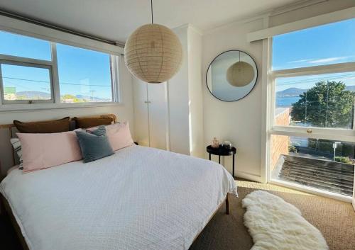 a bedroom with a bed and a large window at The Tassie - Luxury with panoramic water views in Hobart