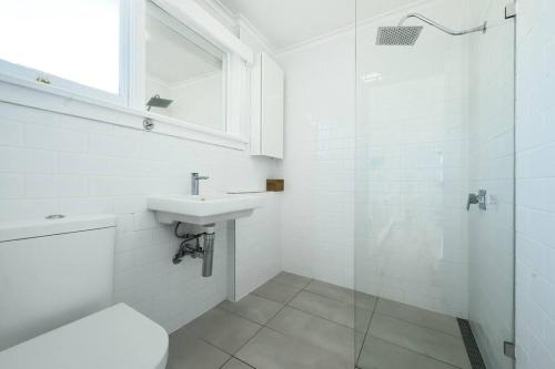 a white bathroom with a sink and a shower at The Tassie - Luxury with panoramic water views in Hobart