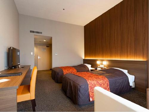 Habitación de hotel con 2 camas y escritorio en Maple Arima en Kobe