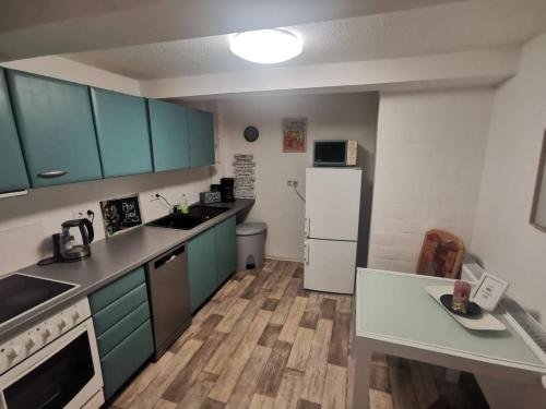 uma cozinha com armários azuis e um frigorífico branco em Günstige, moderne Zimmer im Wanderparadies em Wernigerode