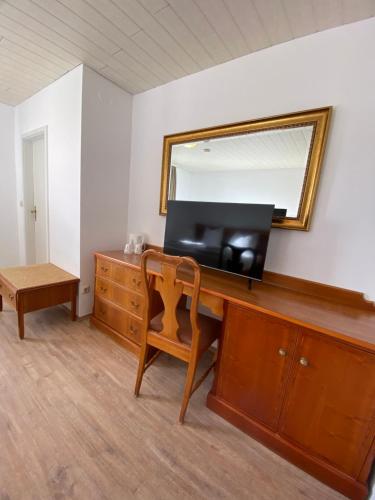 a room with a dresser with a television and a mirror at Hotel Vienenburg in Goslar