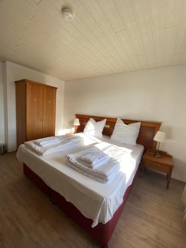 a bedroom with a large bed with white sheets at Hotel Vienenburg in Goslar