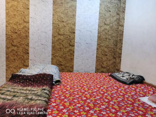 een slaapkamer met een bed en een quilt op de vloer bij Kadiya dharamshala in Mathura