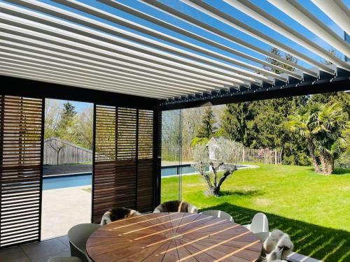 d'une salle à manger avec une table et une vue sur la cour. dans l'établissement Maison de rêve avec piscine à 5 minutes du lac., à Portalban- Dessous