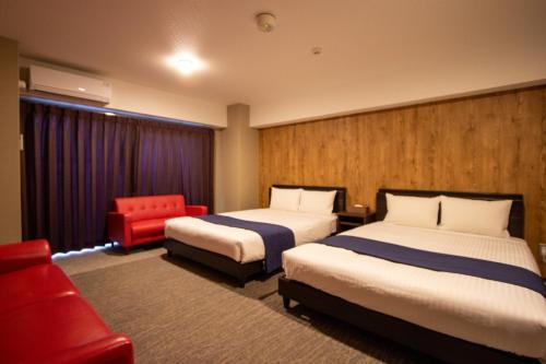 ein Hotelzimmer mit 2 Betten und einem roten Stuhl in der Unterkunft Hotel Fu-Rin in Fukuoka