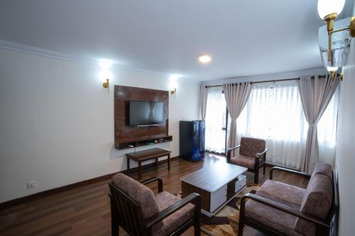 a living room with a tv and chairs and a table at Kathmandu Business Hotel in Kathmandu