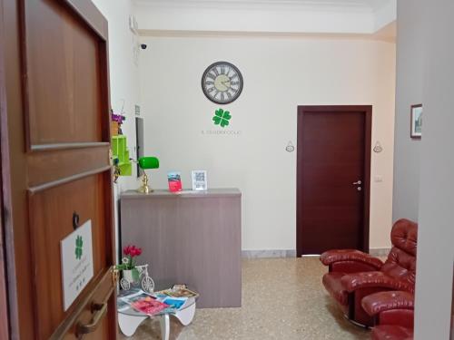 sala de estar con silla y reloj en la pared en Il Quadrifoglio Room& Suite, en Palermo