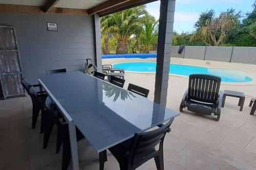 - une table bleue et des chaises en face de la piscine dans l'établissement Villa Folie Douce, accueille 10 pers avec Piscine, à Réthôville
