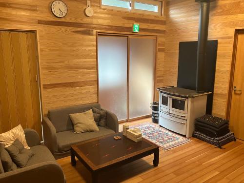 uma sala de estar com um sofá e um fogão em Guesthouse EL CAMPO em Gokase