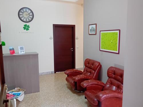 パレルモにあるIl クアドゥリフォリオ ルーム＆スイートの革張りの椅子2脚と時計付きの待合室