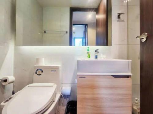 Un baño con inodoro, lavabo y espejo. en AL Define Condo, en Bangkok