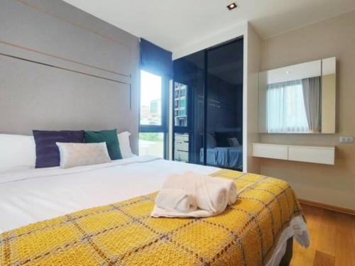 Un dormitorio con una cama grande con una manta amarilla. en AL Define Condo, en Bangkok