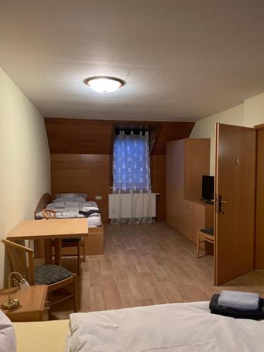 um quarto com três camas e uma mesa e uma janela em Pension Sandsteinhöhle em Walldorf