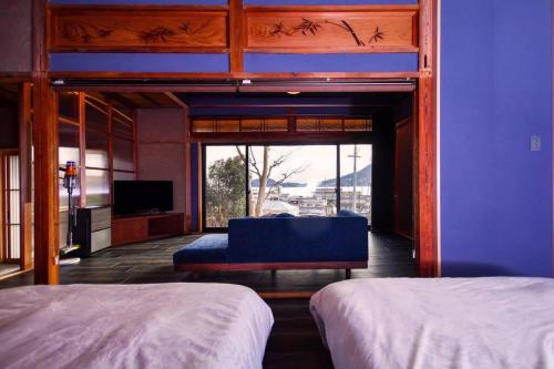 a bedroom with two beds and a large window at 由良民泊島宿 in Matsuyama