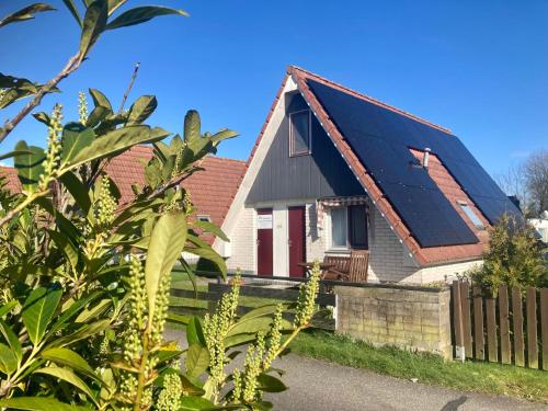 a house with a black roof with a fence at Holiday House Platz an der Sonne for 6 people near Lake Lauwersmeer in Oostmahorn
