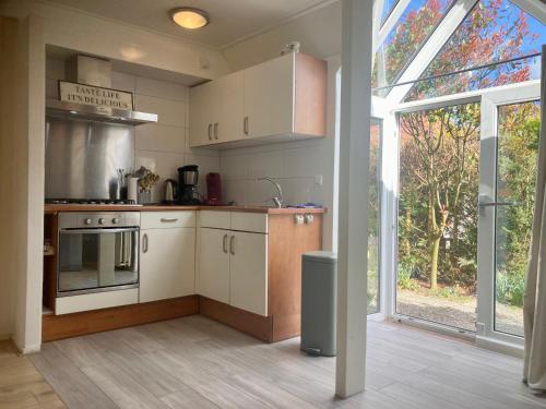 cocina con armarios blancos y ventana grande en Dijkrose, en Oostmahorn