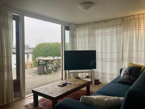 a living room with a couch and a tv and a table at Chalet Valentina directly on the Lauwersmeer in Anjum