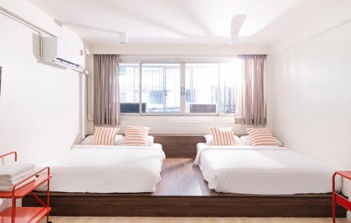 two beds in a room with a window at Theme Stories - Boutique Guesthouse in Bangkok