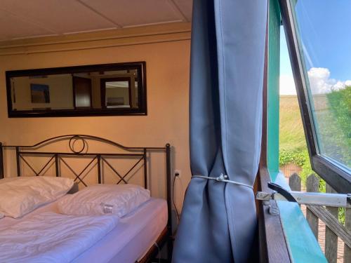 uma cama num quarto com uma janela e uma cortina em 4 pers Holiday Home Hilla with winter garden in front of the dike directly on the Lauwersmeer em Anjum