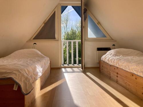 1 Schlafzimmer mit 2 Betten und einem großen Fenster in der Unterkunft Grachthaus 6pers House with a private terrace and garden by the Lauwersmeer in Anjum