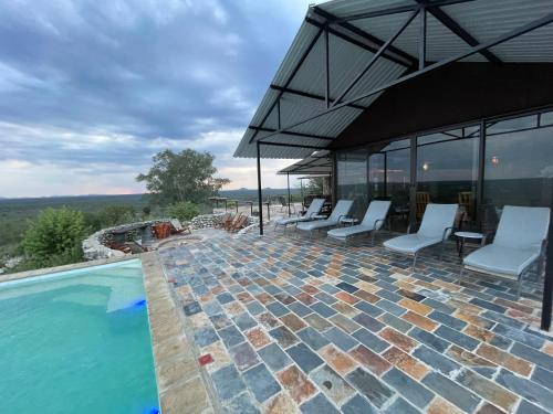 an outdoor swimming pool with chairs and an umbrella at Aloegrove Safari Lodge in Otjiwarongo