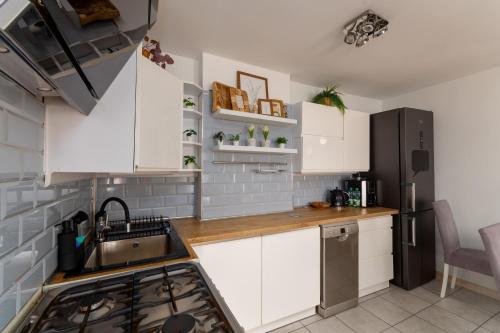 a kitchen with white cabinets and a stainless steel refrigerator at Pod Trzynastką Cosy Apartment in Jelenia Góra