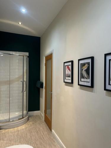 a bathroom with a shower and paintings on the wall at Beautifully presented Victorian Apartment within walking distance to Llandudno beach in Llandudno