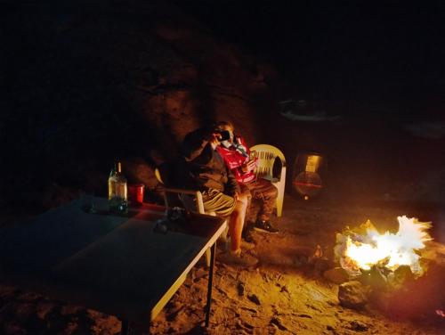 a man sitting in a chair next to a fire at Mag Bay Paradise in San Carlos