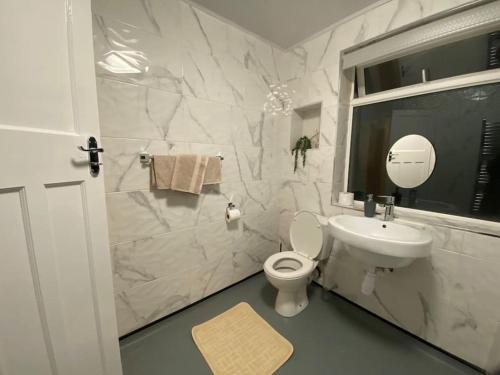 La salle de bains blanche est pourvue de toilettes et d'un lavabo. dans l'établissement Spacious 4BR Home Near The NEC The Airport and Heartlands Hospital, à Birmingham