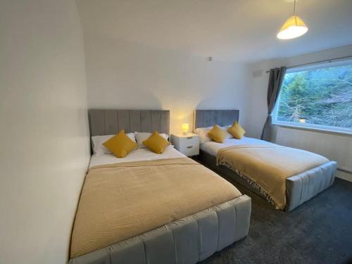 two beds in a hotel room with yellow pillows at Spacious 4BR Home Near The NEC The Airport and Heartlands Hospital in Birmingham