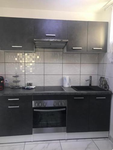 uma cozinha com armários pretos e um forno com placa de fogão em Appartement au RDC d’une maison em Privas