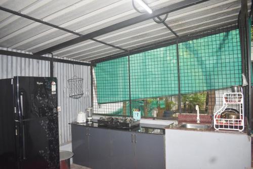 a kitchen with a black refrigerator and a green window at Mi Casa Tu Casa Homestay in Cochin
