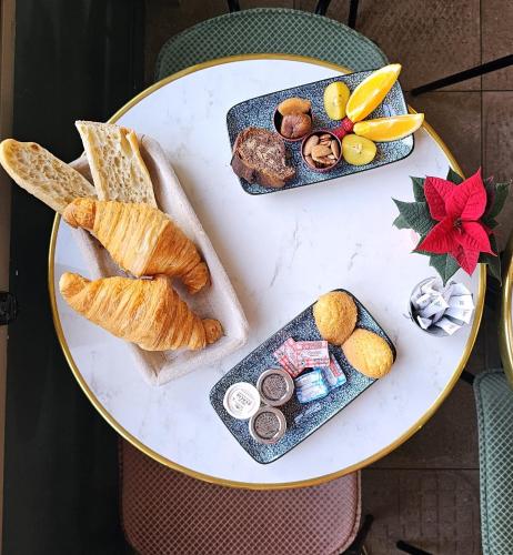 a table topped with plates of bread and pastries at Hotel des Iris in Auvers-sur-Oise