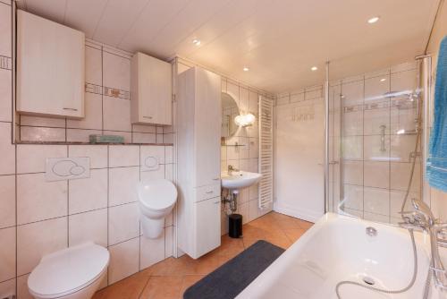 a bathroom with a tub and a toilet and a sink at Ferienwohnung im Arfetal in Bad Berleburg