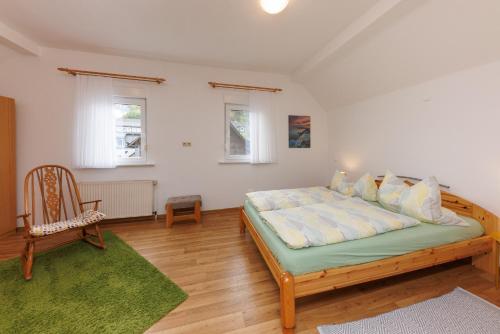 a bedroom with a large bed and a chair at Ferienwohnung im Arfetal in Bad Berleburg