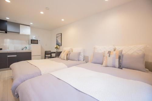two white beds in a room with a kitchen at Shinjuku Ryokan Retreat丶Local Tokyo Experience & Short Trips Hub丶walk to Shinjuku station EoE4 in Tokyo