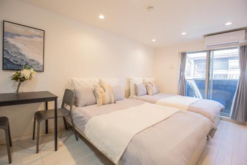a bedroom with two beds and a table and a window at Shinjuku Ryokan Retreat丶Local Tokyo Experience & Short Trips Hub丶walk to Shinjuku station EoE4 in Tokyo