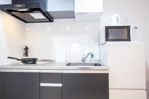 a kitchen with a sink and a microwave at Shinjuku Ryokan Retreat丶Local Tokyo Experience & Short Trips Hub丶walk to Shinjuku station EoE4 in Tokyo