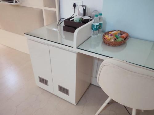 a white desk with a glass top and a chair at Hotel Hindustan Inn in Kuchaiburi