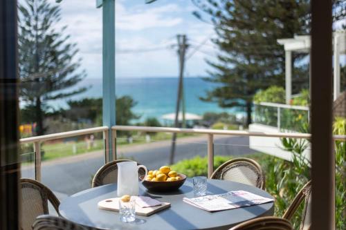 a blue table with a bowl of fruit on a balcony at Sandilands One - Oceanstays in Yamba