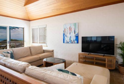 a living room with a couch and a flat screen tv at Sandilands One - Oceanstays in Yamba