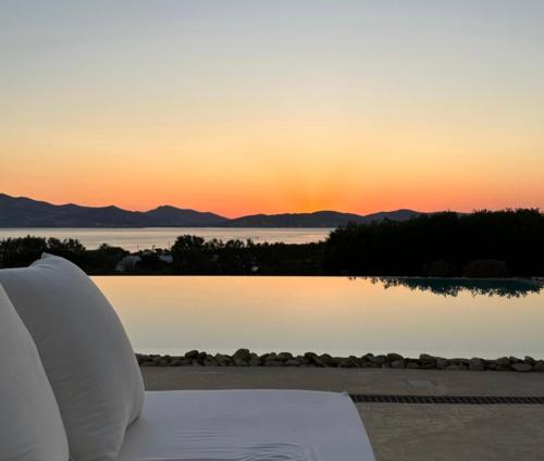 a white couch sitting next to a lake at sunset at Villa Siena in Kampos Paros