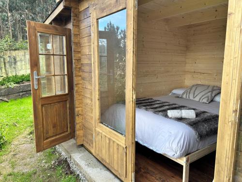 a bed in a wooden cabin with a window at Finca Las Bimbas in Oleiros