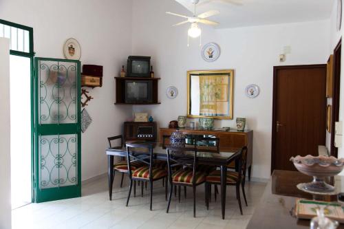 a dining room with a table and chairs and a tv at La Casa Nel Parco in SantʼAgata di Militello