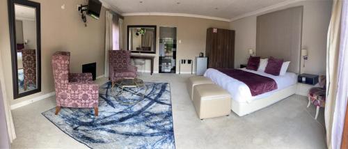 a bedroom with a bed and a couch and chairs at Kerala Hotel in Bloemfontein