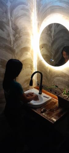 a person washing their hands in a sink in a cave at ALCAVA Rustic Kubo Huts in Dipolog
