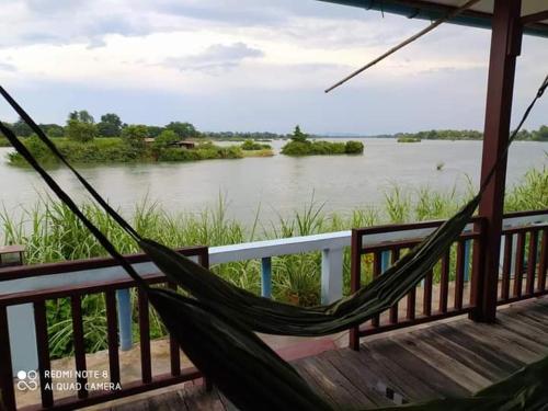 a hammock on a balcony overlooking a river at Sunset bungalows in Muang Không