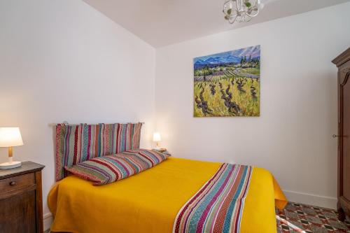 a bedroom with a yellow bed with a painting on the wall at La maison des Remparts in Saint-Jean-de-Barrou