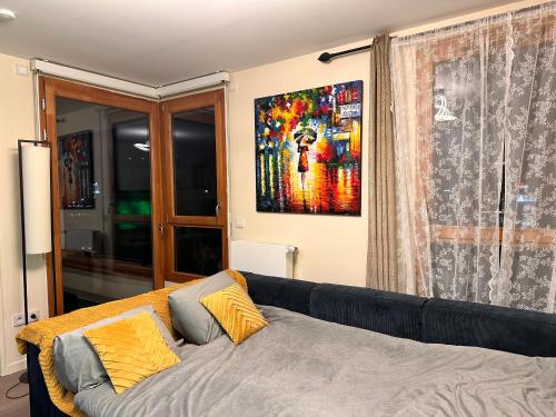パリにあるCharmant appartement sacré cœur avec parking gratuitのソファ付きのベッドルーム1室、壁に絵画が飾られています。