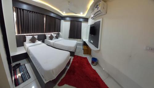 a small room with two beds and a flat screen tv at signature hotel in Ahmedabad